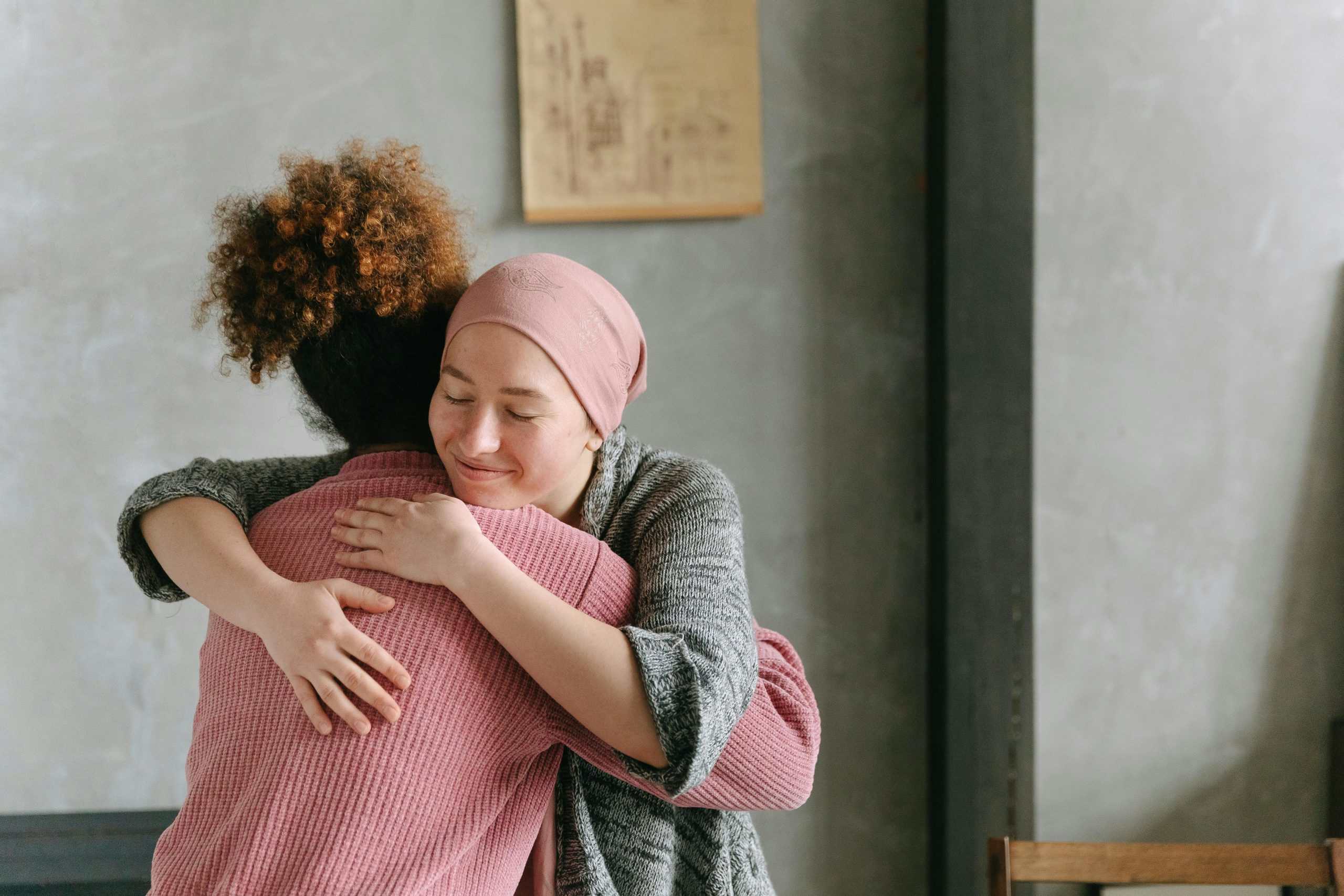 Two women embracing each other with warmth and love, symbolizing support and care indoors.